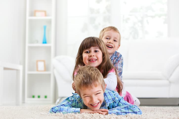 Group of happy preschool children lying down on the floor in domestic room.
